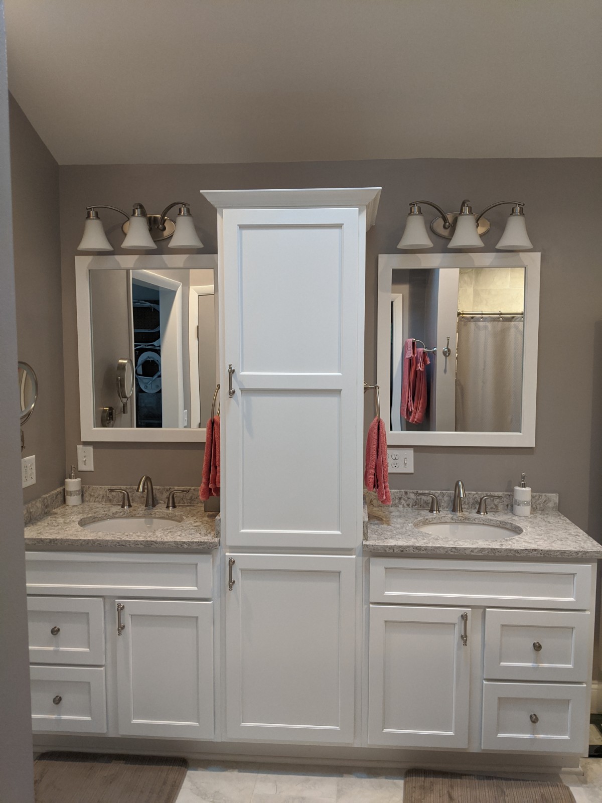 This picture is showing the double vanities now on one wall with the linen cabinet between them.  Prevents the vanities from sticking out into the room and blocking the flow.  White painted vanities with quartz tops are elegant and beautiful as well as functional