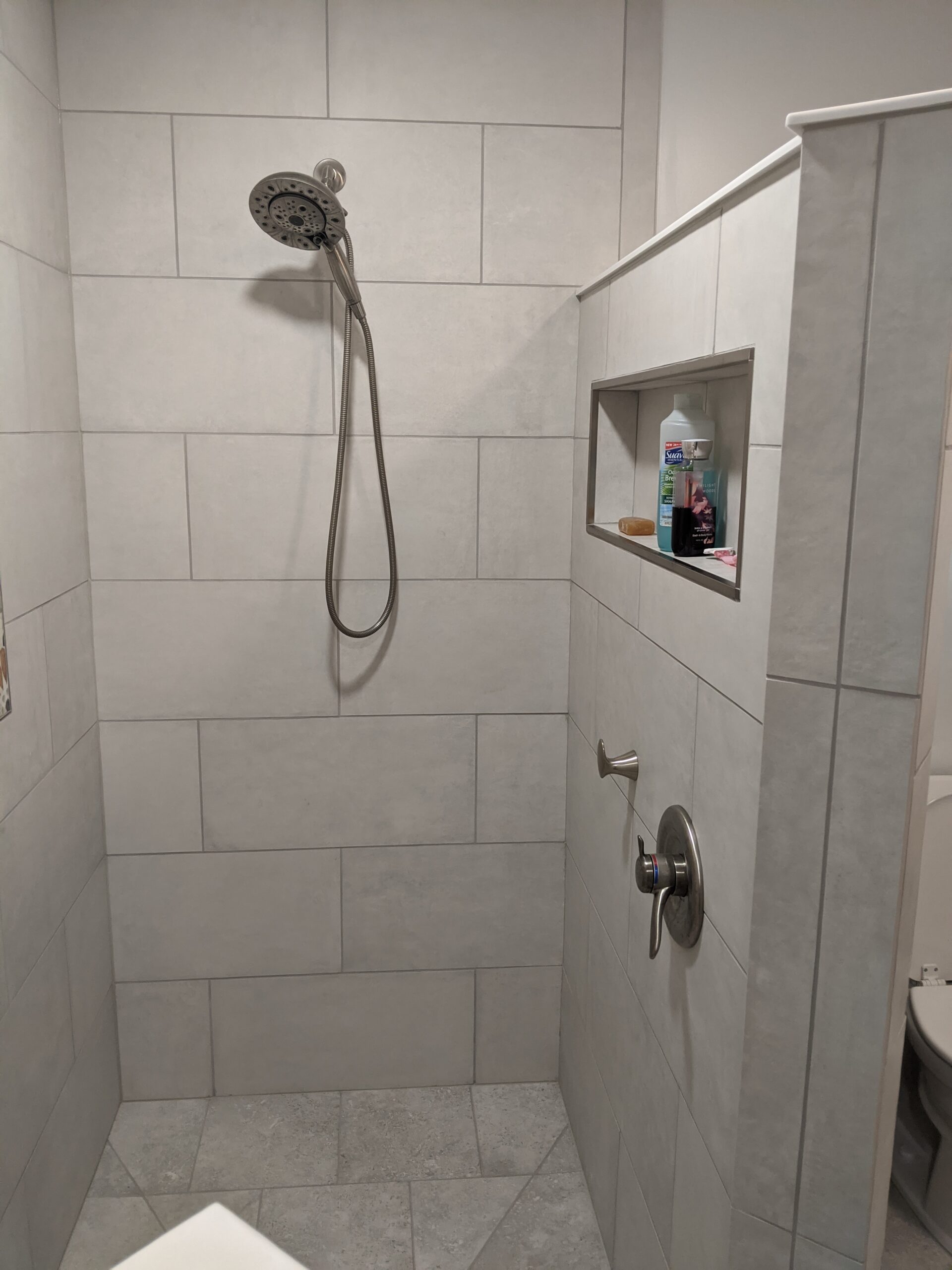 The tiled shower has a custom niche to hold all the shower items