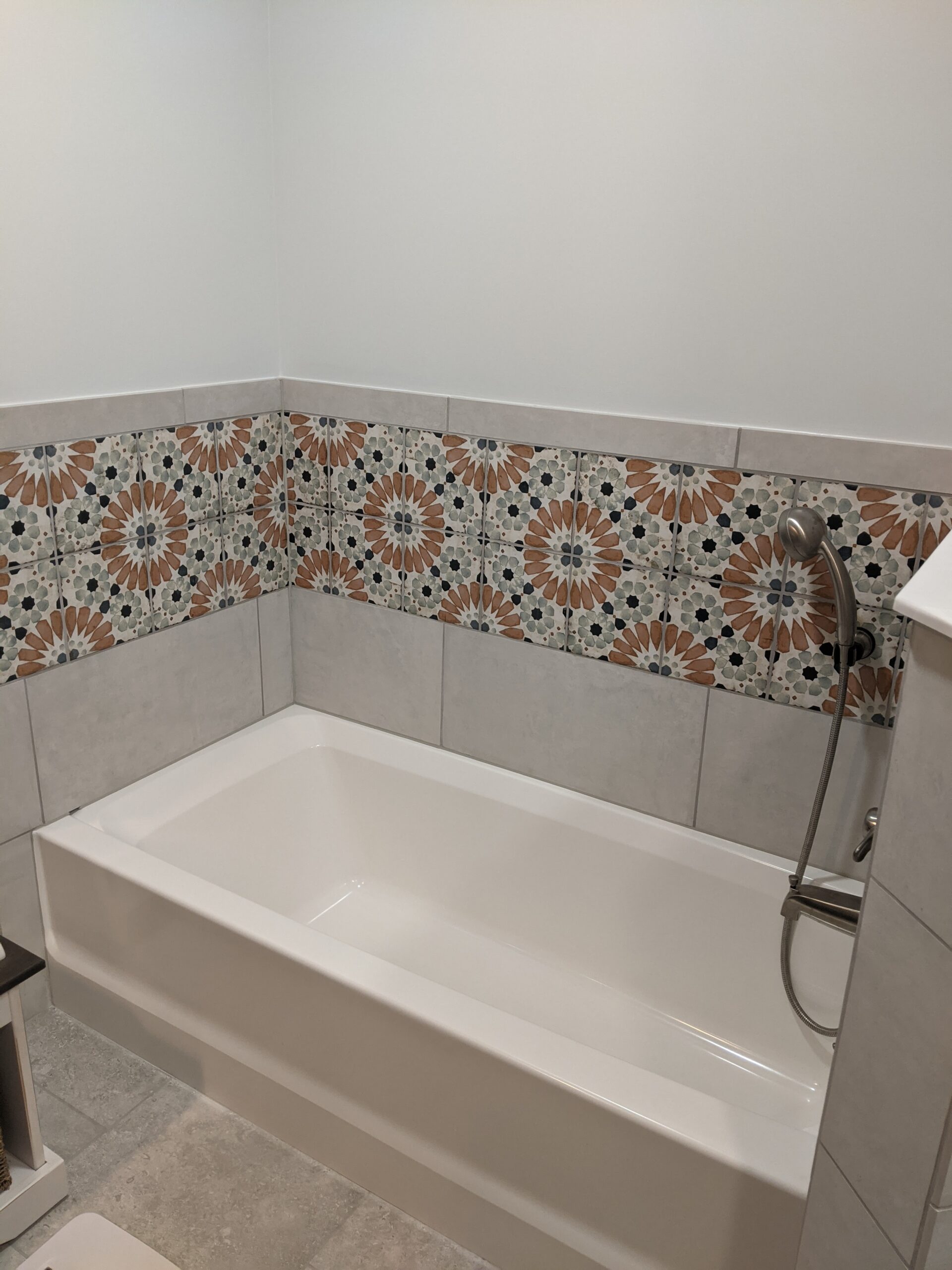 The tub area is now a standard tub with tile and decorative tile surrounding it.