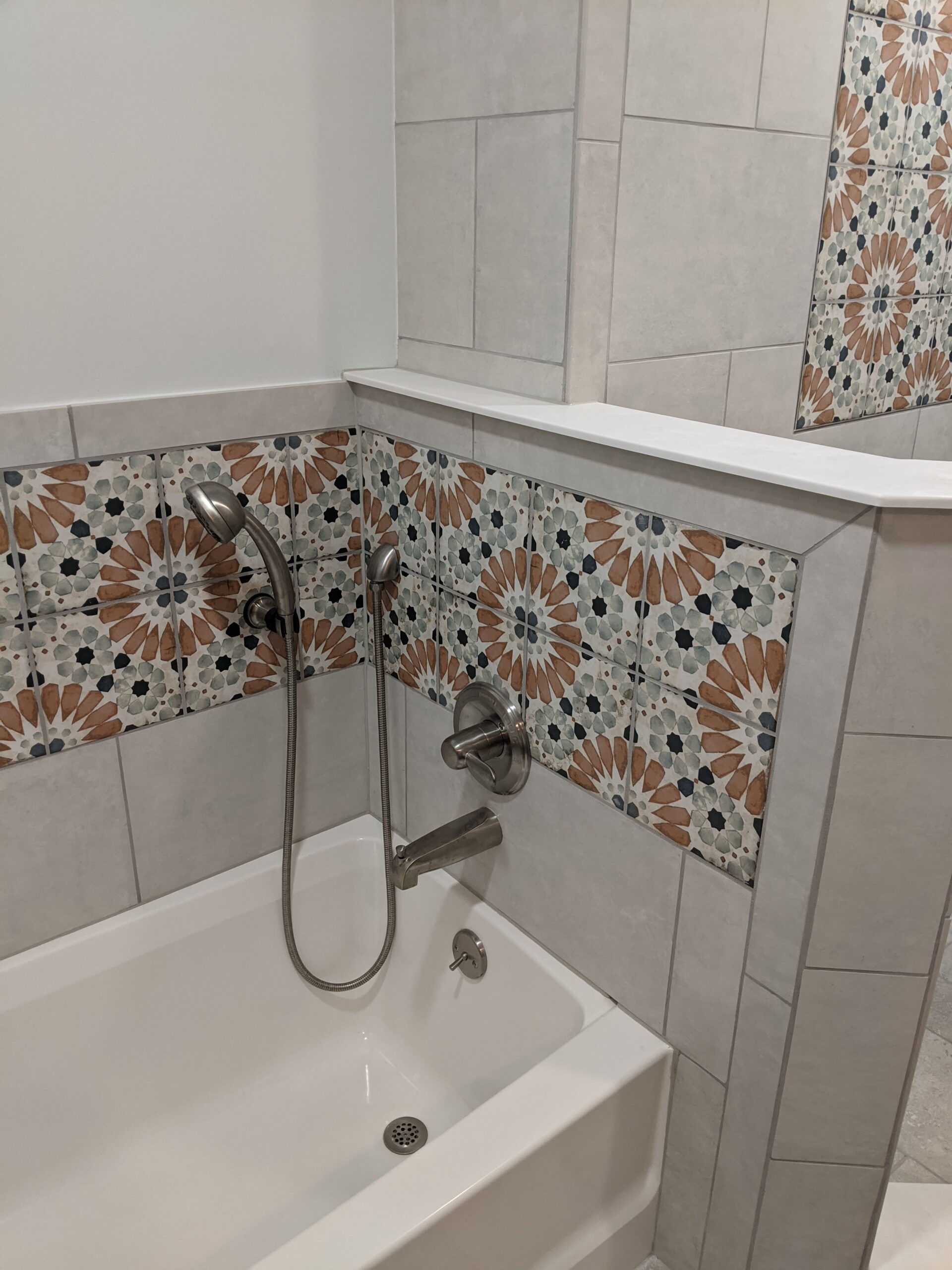 The tub area is now a standard tub with tile and decorative tile surrounding it with a hand held and new fixtures.