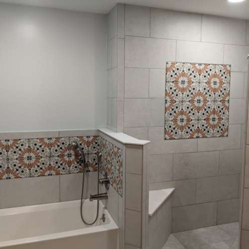 Tiled walls with decorative tile inserts allow the shower and tub areas to flow into eachother