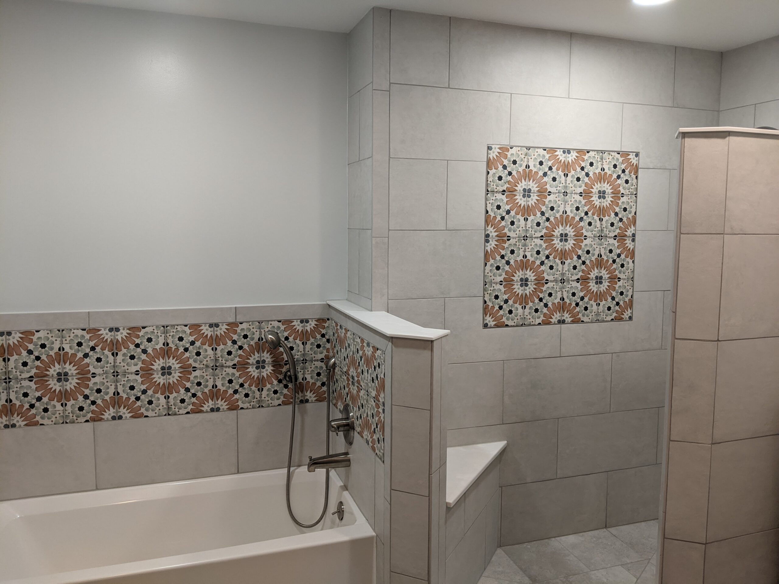 Tiled walls with decorative tile inserts allow the shower and tub areas to flow into eachother